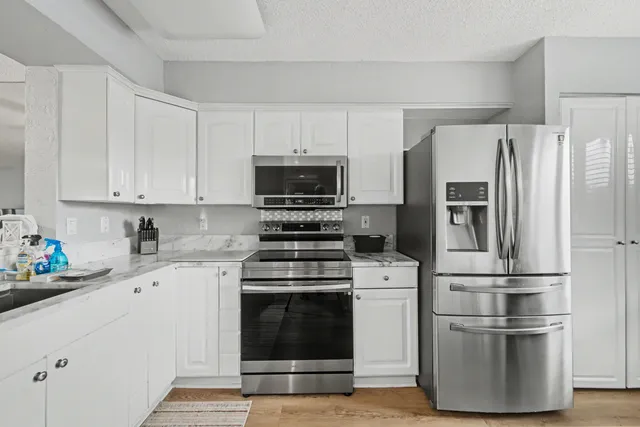 a kitchen with cabinets stainless steel appliances and wooden floor