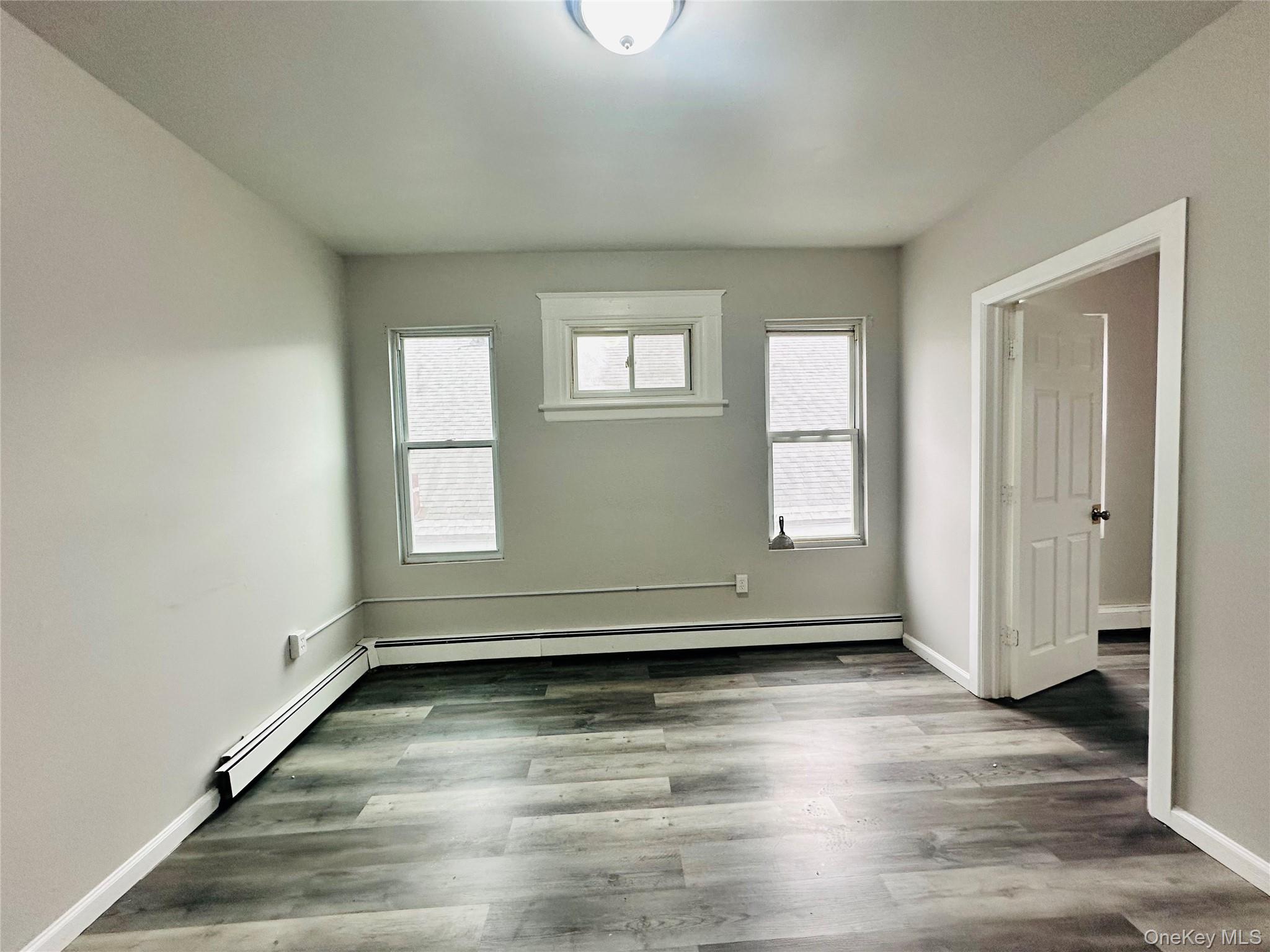 7 Franklin Street, Unit #7 Poughkeepsie, NY 12601 - Photo 3 of 11 an empty room with wooden floor and windows