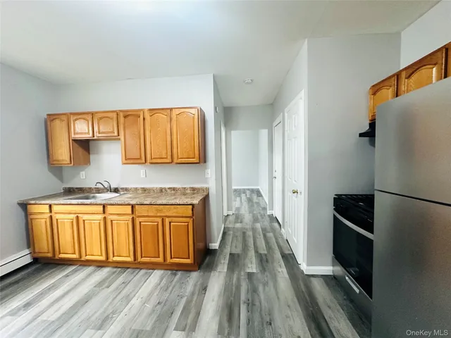 a kitchen with stainless steel appliances granite countertop a refrigerator a stove and a sink with wooden floor