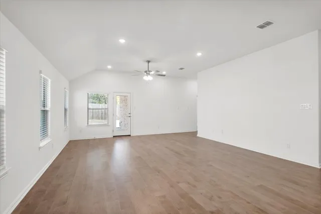 a view of an empty room with wooden floor and windows