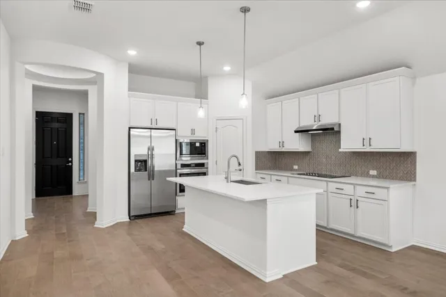 a kitchen with refrigerator a stove and white cabinets