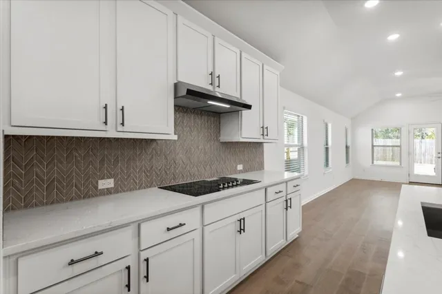 a kitchen with stainless steel appliances granite countertop white cabinets and a stove