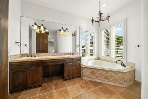 a spacious bathroom with a tub double sink large mirror and a large window
