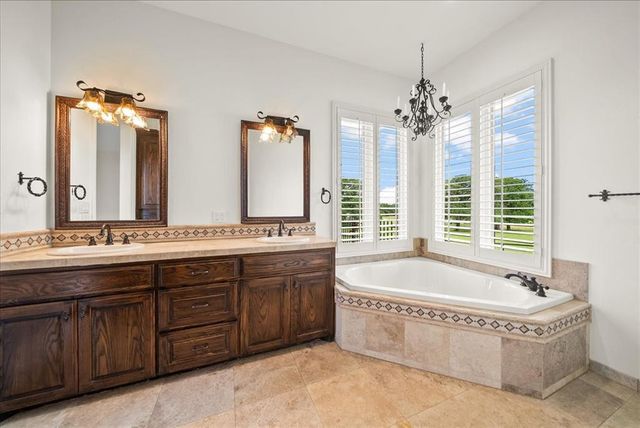 a spacious bathroom with a tub sink and mirror