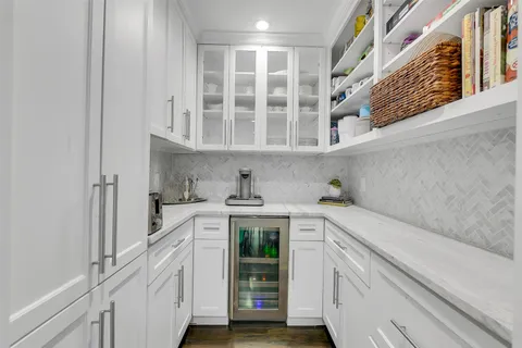 a large kitchen with stainless steel appliances a stove a sink a microwave a dining table and chairs with wooden floor