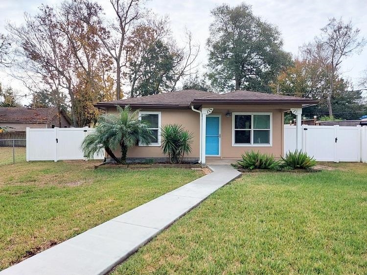 View of front of home featuring a gate, stucco siding, and roof with shingles