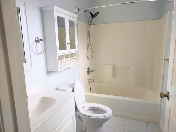 a bathroom with a granite countertop bathtub shower sink vanity and toilet