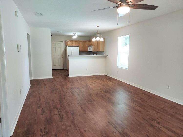 63 Anderson Street St. Augustine, FL 32084 - Photo 2 of 16 Unfurnished living room featuring a chandelier, dark wood-style floors, and a ceiling fan