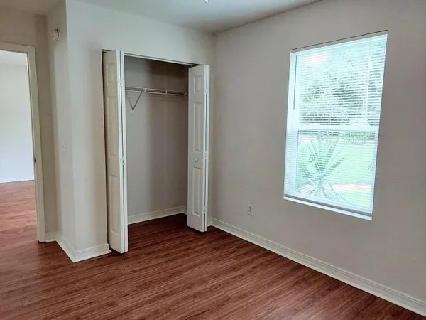 an empty room with wooden floor closet and windows