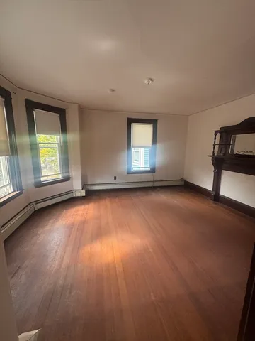an empty room with a hardwood and windows