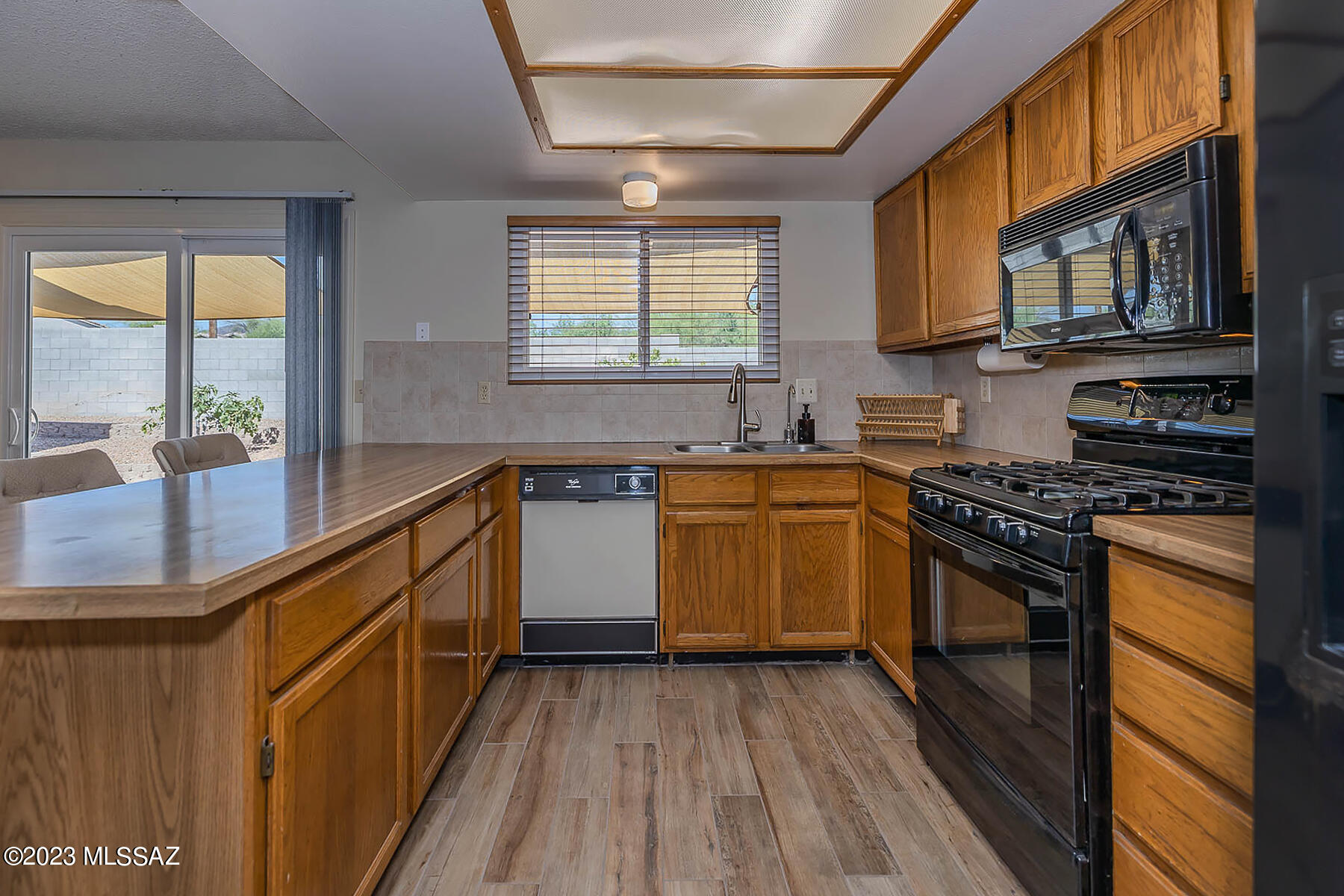 1286 South Gecko Road Tucson, AZ 85713 - Photo 7 of 27 a kitchen with stainless steel appliances granite countertop a stove a sink dishwasher and a microwave oven with cabinets