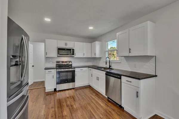 a kitchen with granite countertop white cabinets and stainless steel appliances