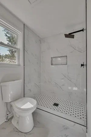 a white toilet sitting next to a shower