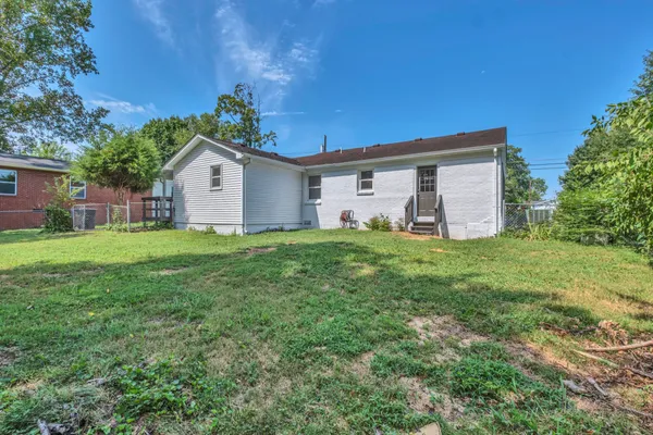 a front view of house with yard and trees in the background
