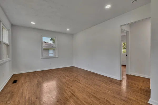 an empty room with wooden floor and windows