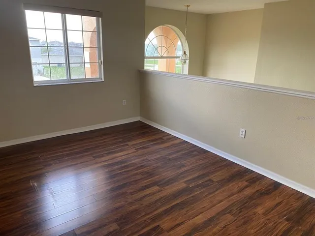 an empty room with wooden floor windows and entrance