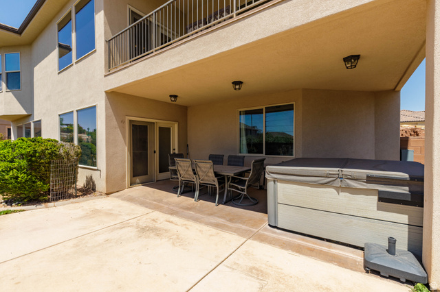 2005 West 450 S Circle St. George, UT 84770 - Photo 34 of 57 Lower-level covered patio featuring a built-in hot tub, concrete flooring, exterior lighting fixtures, and direct access to interior spaces through a glass-paneled door