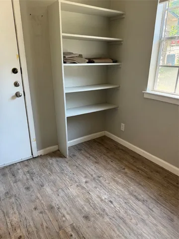 a view of an empty room with a window and wooden floor