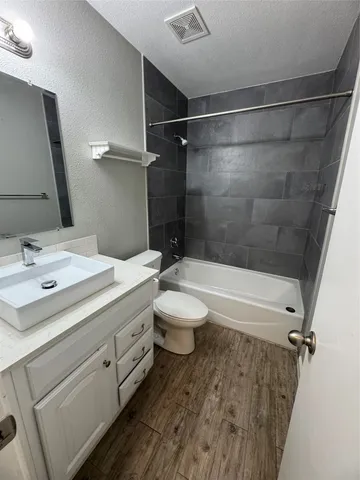 a bathroom with a granite countertop sink toilet a mirror and shower