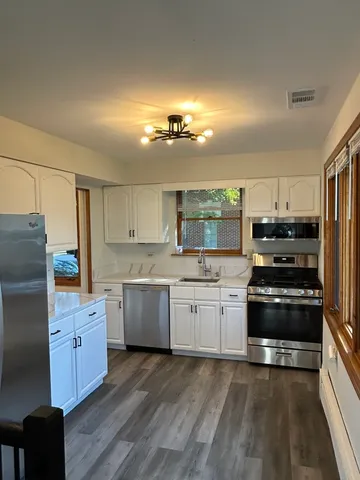 a kitchen with granite countertop a refrigerator stove top oven and sink