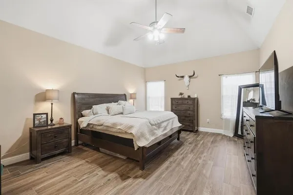 a spacious bedroom with a bed and wooden floor