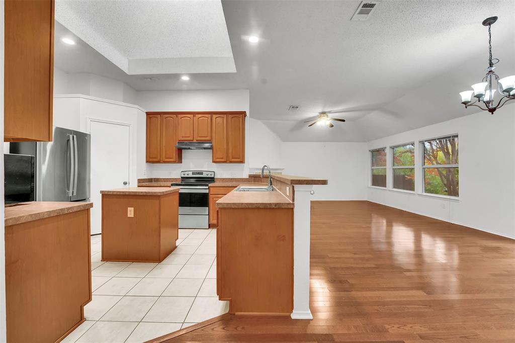 4507 Stones River Road Grand Prairie, TX 75052 - Photo 16 of 28 a kitchen with sink a refrigerator and chairs