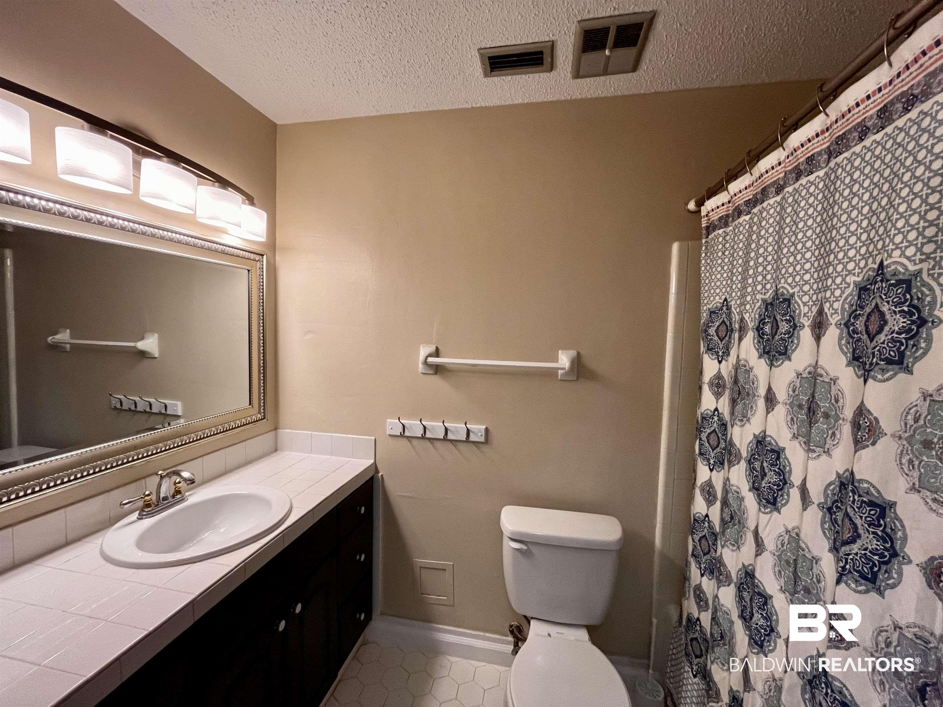 6429 Pinehurst Run Mobile, AL 36608 - Photo 13 of 15 Bathroom vanity with a white tile countertop, integrated sink, and dark wood-finish cabinetry