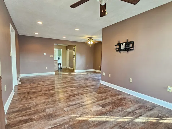 an empty room with wooden floor and fan