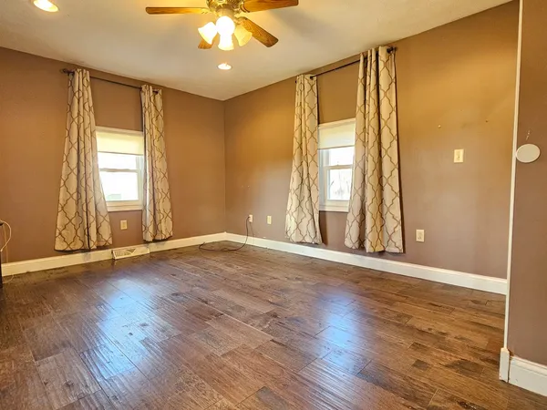 an empty room with wooden floor and windows
