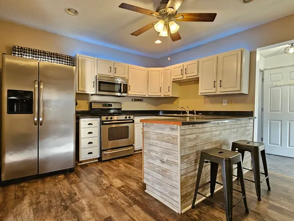 a kitchen with granite countertop a refrigerator stove top oven and sink