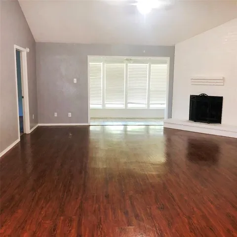 a view of an empty room with wooden floor and a fireplace
