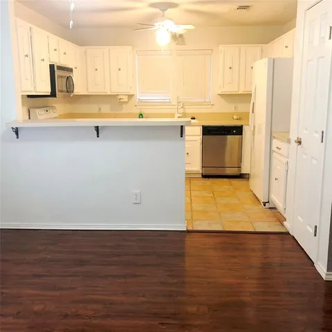 a large kitchen with stainless steel appliances granite countertop a stove a sink dishwasher and a refrigerator with wooden floor