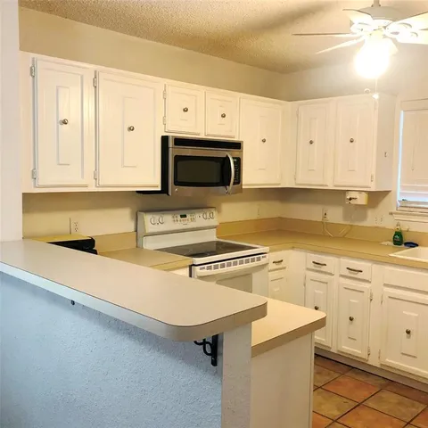 a kitchen with granite countertop a sink white cabinets and white appliances