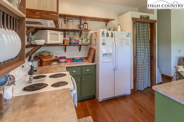 a kitchen with stainless steel appliances granite countertop a stove a refrigerator a kitchen island a stove and a dining table with wooden floor