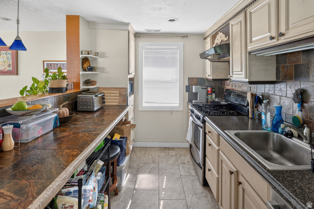 730 East 200 North Logan, UT 84321 - Photo 7 of 28 Galley-style kitchen featuring granite-look countertops, subway tile backsplash, and light-toned cabinetry