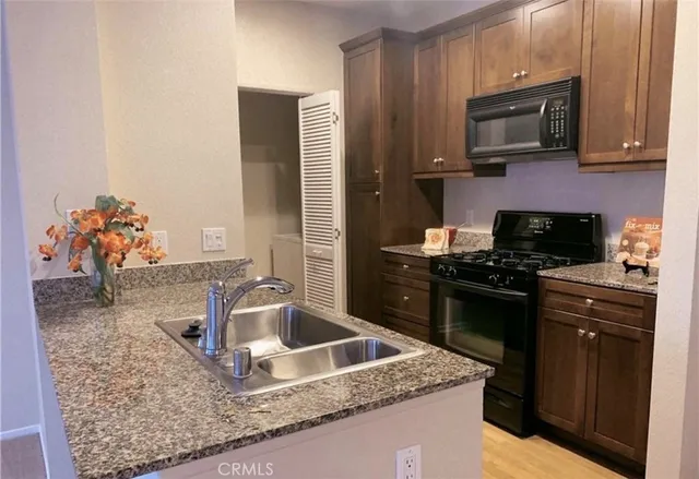 a kitchen with granite countertop stainless steel appliances a stove sink and microwave