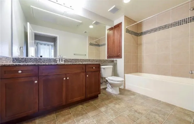 a spacious bathroom with a granite countertop sink toilet mirror and bathtub