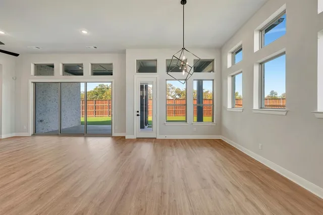 a view of an empty room with window and chandelier fan