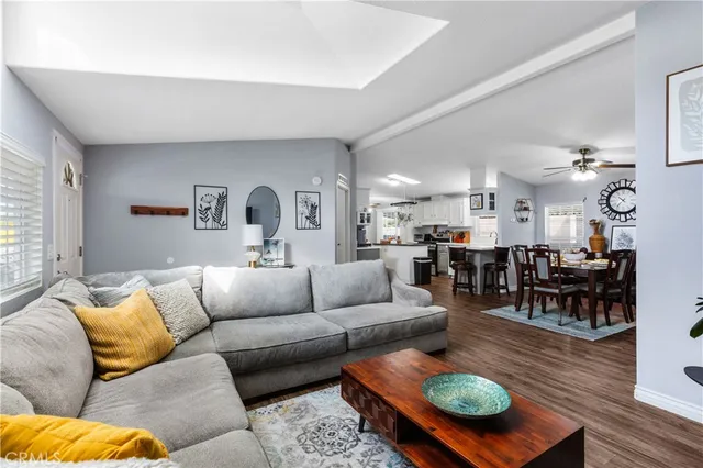 a living room with furniture kitchen view and a large window