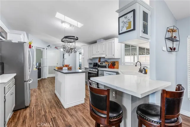 a kitchen with stainless steel appliances a sink a stove a refrigerator cabinets and a dining table