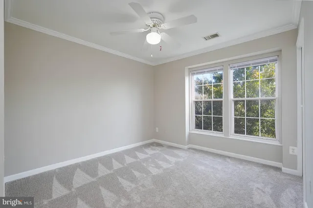 an empty room with windows and ceiling fan