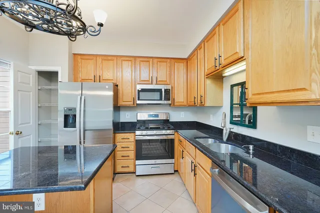 a kitchen with stainless steel appliances granite countertop a sink a stove and a refrigerator