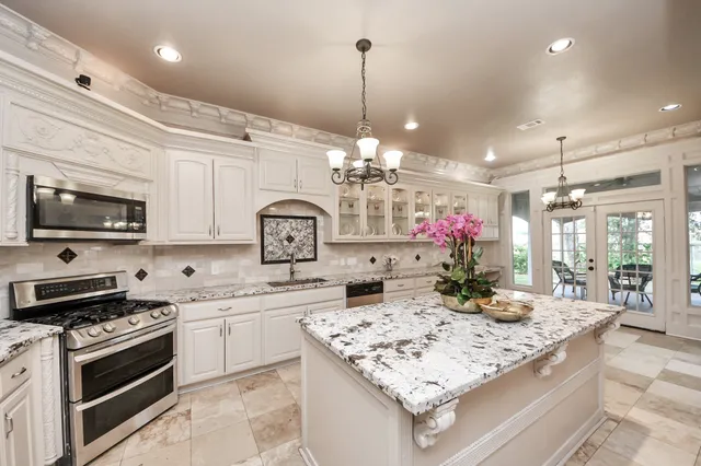 a kitchen with kitchen island granite countertop a sink stove and white cabinets