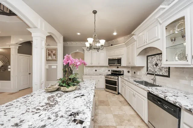a kitchen with kitchen island granite countertop a stove a sink and a white cabinets