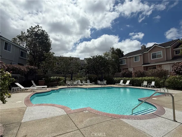 a view of a swimming pool with lawn chairs and a fire pit
