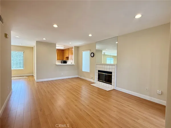an empty room with wooden floor fireplace and windows