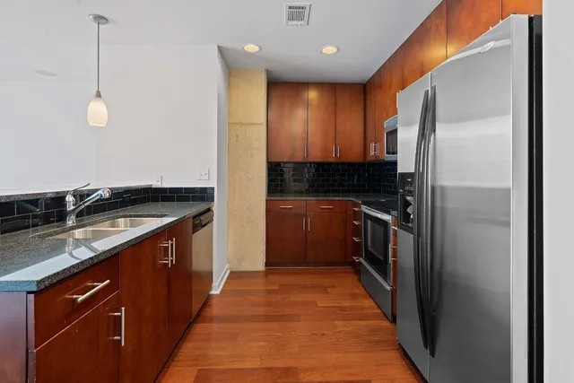 a kitchen with stainless steel appliances granite countertop a sink and a refrigerator