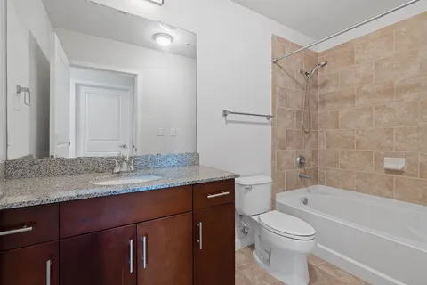 a bathroom with a granite countertop sink toilet and shower