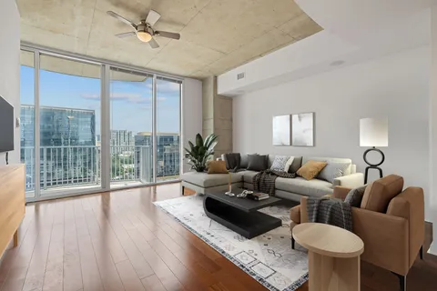 a living room with furniture a large window and wooden floor