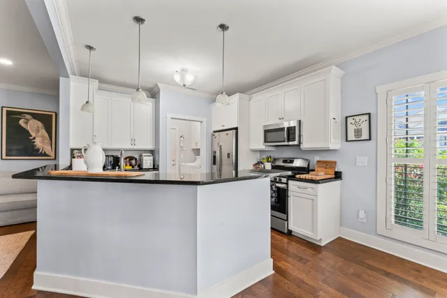 a kitchen with stainless steel appliances kitchen island a refrigerator a stove a sink and a wooden floors